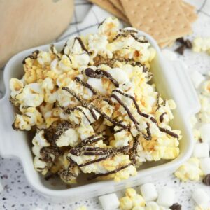 S'mores popcorn with chocolate drizzle in a white bowl.