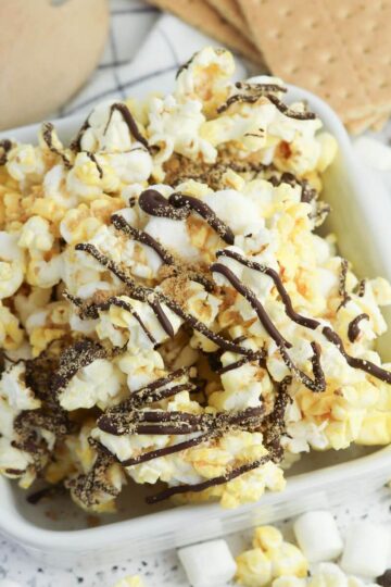S'mores popcorn with chocolate drizzle in a white bowl.